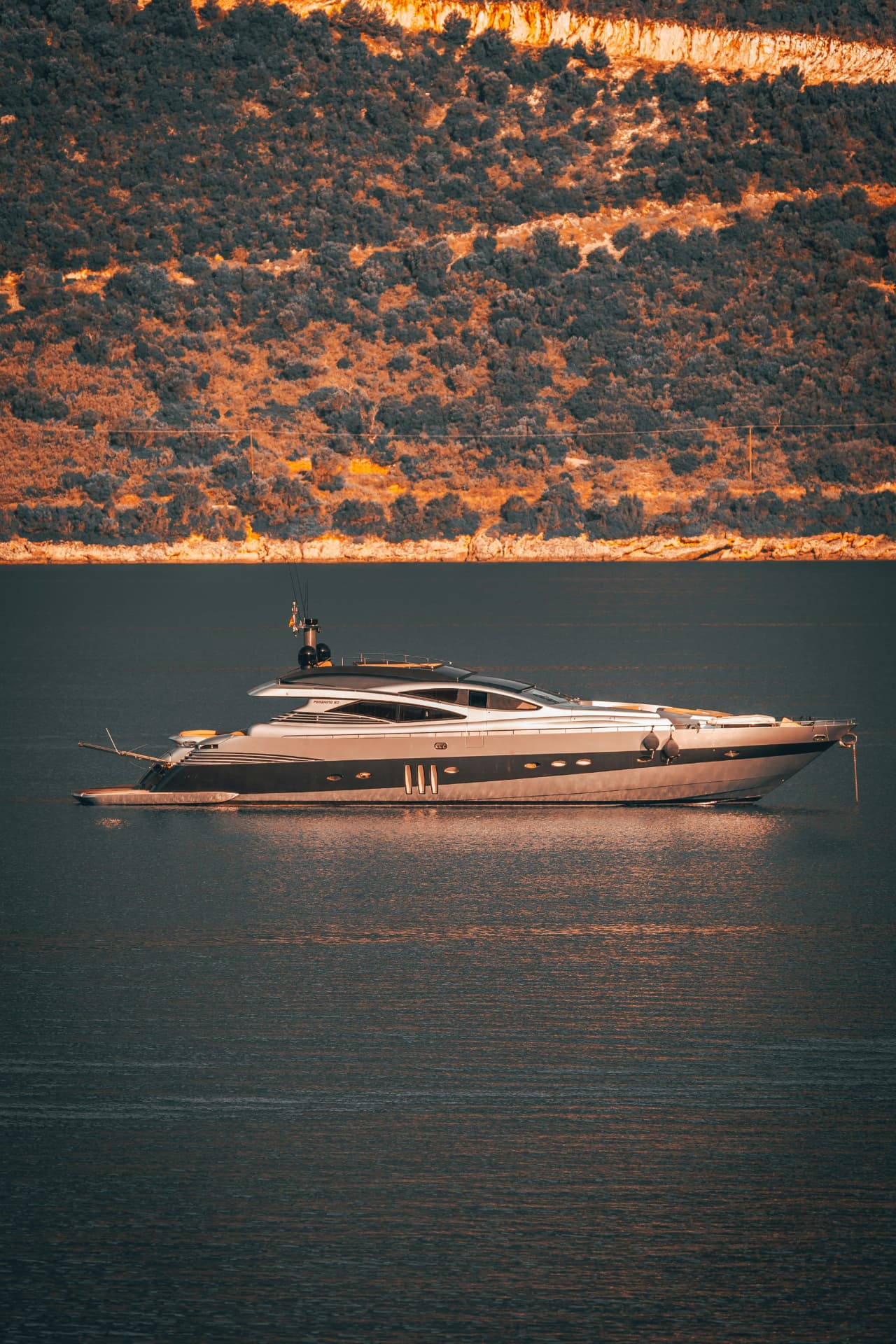 Yacht at anchor in a sunlit bay at golden hour